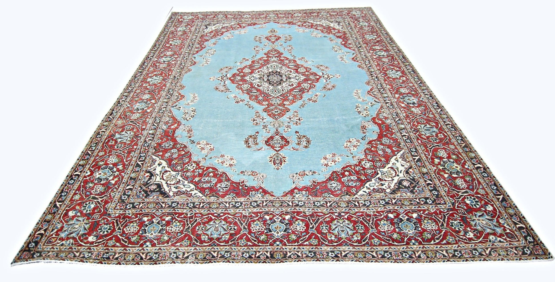 A vintage Persian Kerman rug featuring a central medallion on a light blue field with floral motifs.