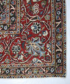 A vintage Persian Kerman rug featuring an intricate floral pattern in red, blue, and cream tones.