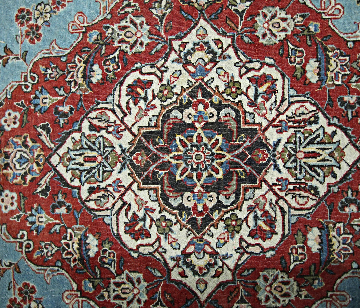 A vintage Persian Kerman rug featuring an intricate central medallion with floral motifs.