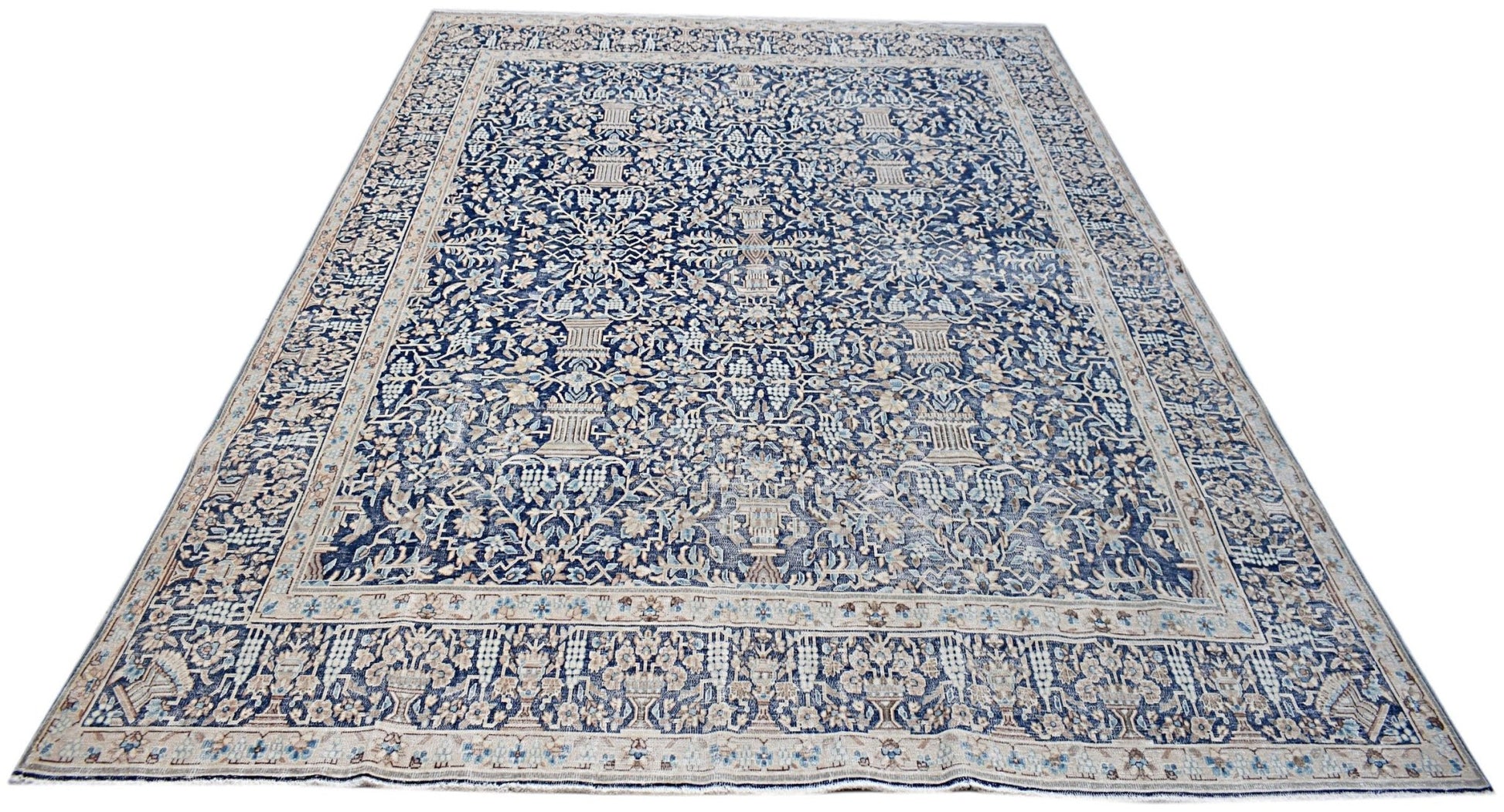 A vintage Persian Kerman rug featuring an intricate blue and cream floral pattern.