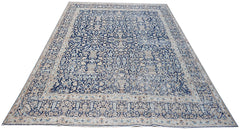 A vintage Persian Kerman rug featuring an intricate blue and cream floral pattern.