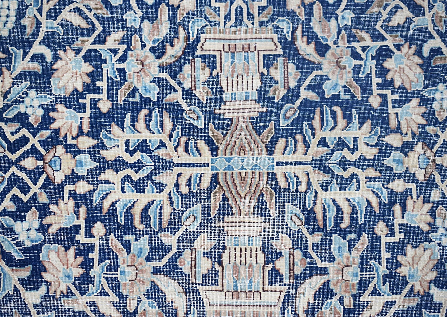A vintage Persian Kerman rug featuring an intricate blue floral pattern with symmetrical motifs.