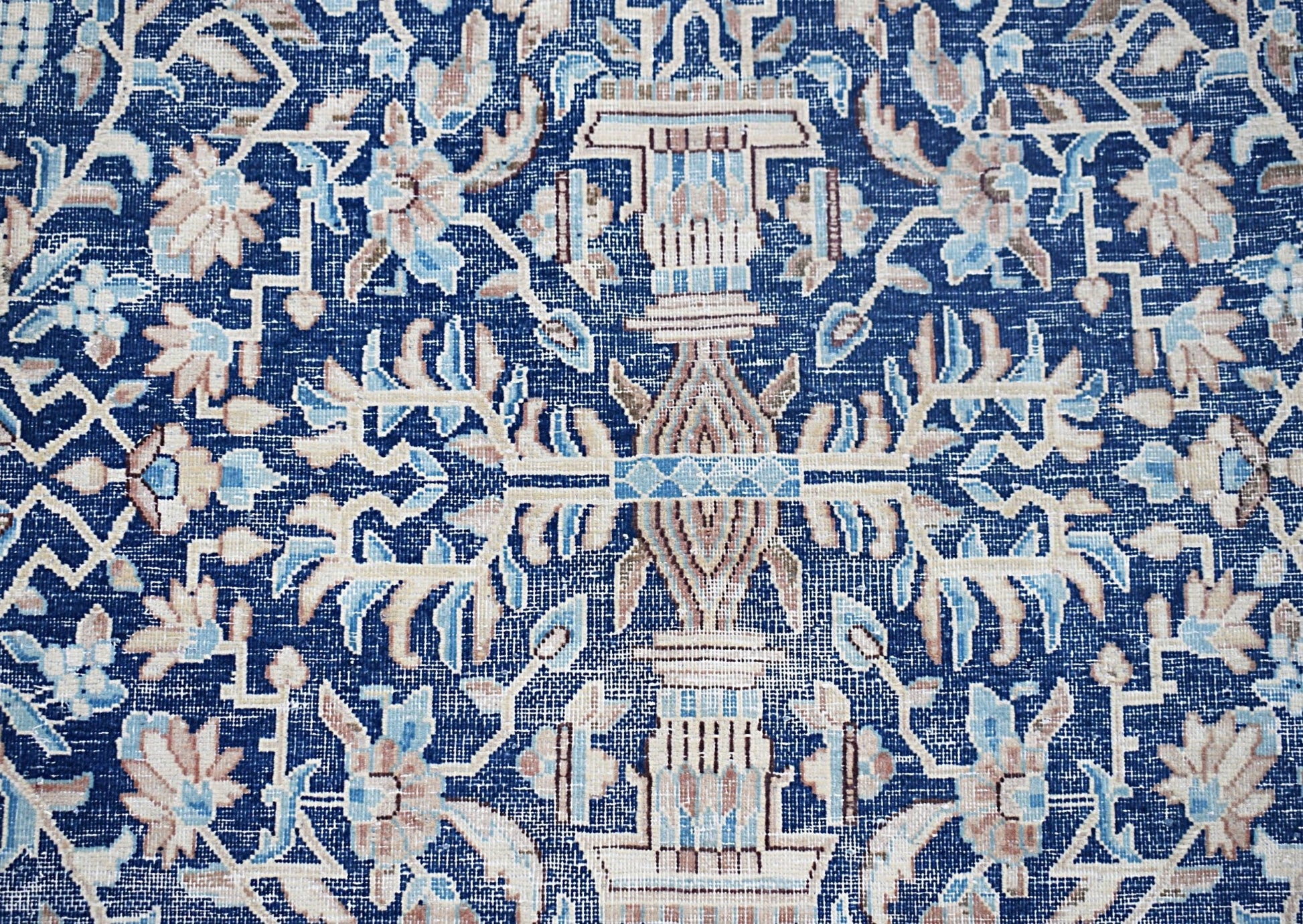 A vintage Persian Kerman rug featuring an intricate blue floral pattern with symmetrical motifs.