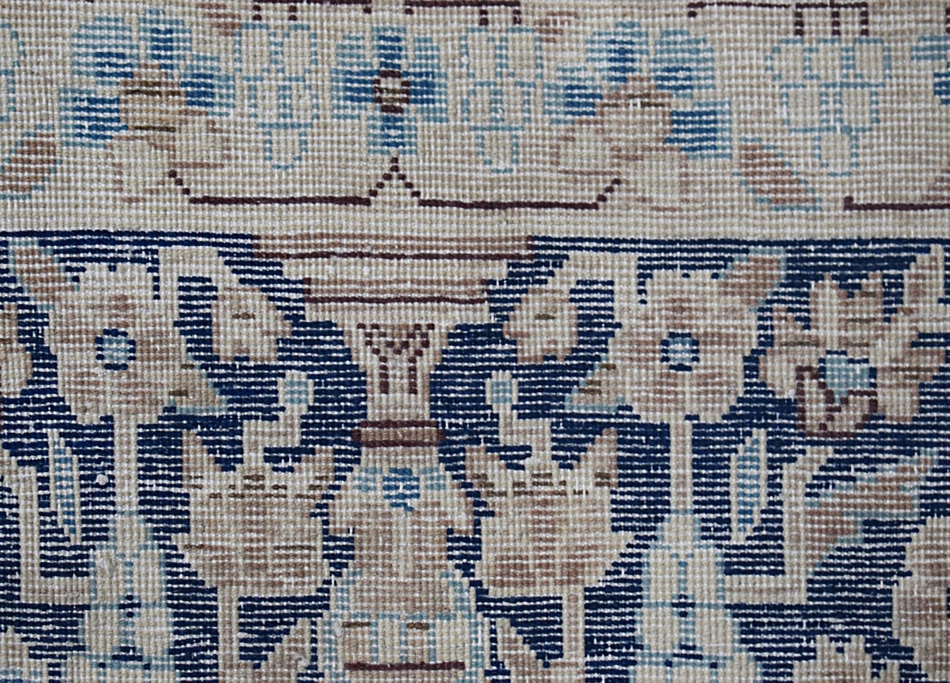 A close-up of a vintage Persian Kerman rug featuring intricate floral patterns in blue and beige.