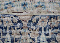 A close-up of a vintage Persian Kerman rug featuring intricate floral patterns in blue and beige.
