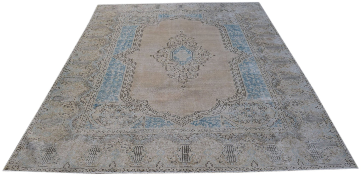 A vintage Persian Kerman rug featuring a central medallion and floral motifs in blue and beige.