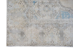 A vintage Persian Kerman rug featuring a faded floral medallion design in beige and soft blue.