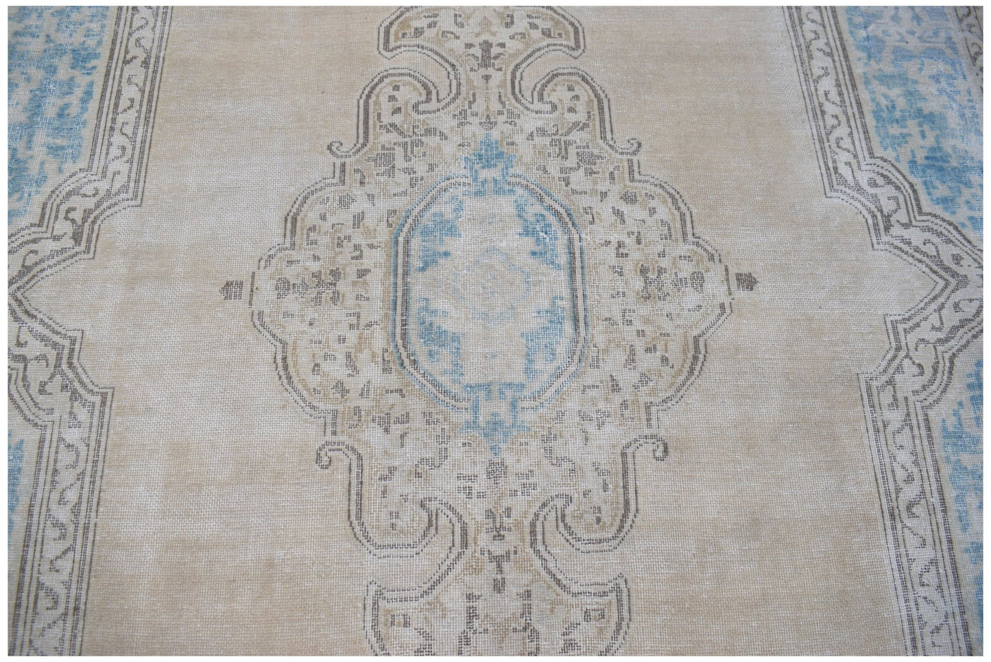 A vintage Persian Kerman rug featuring a central medallion in blue and beige tones.