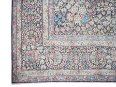 A vintage Persian Kerman rug featuring an intricate floral pattern in soft pink and blue tones.