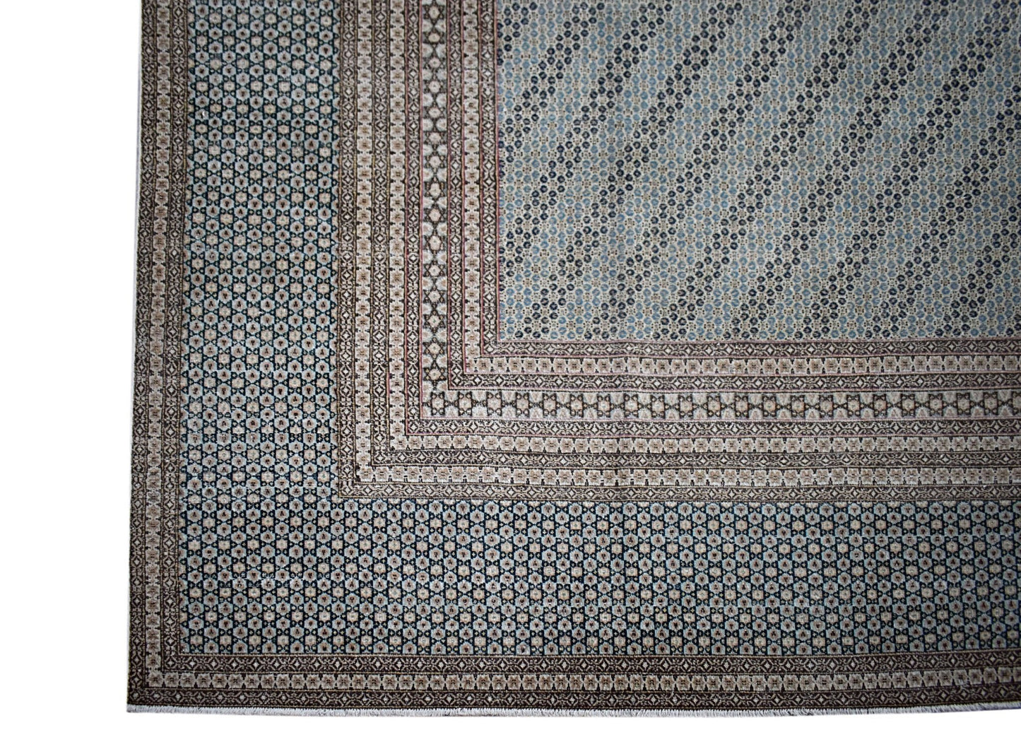 A vintage Persian Kerman rug featuring intricate geometric patterns in blue and beige tones.