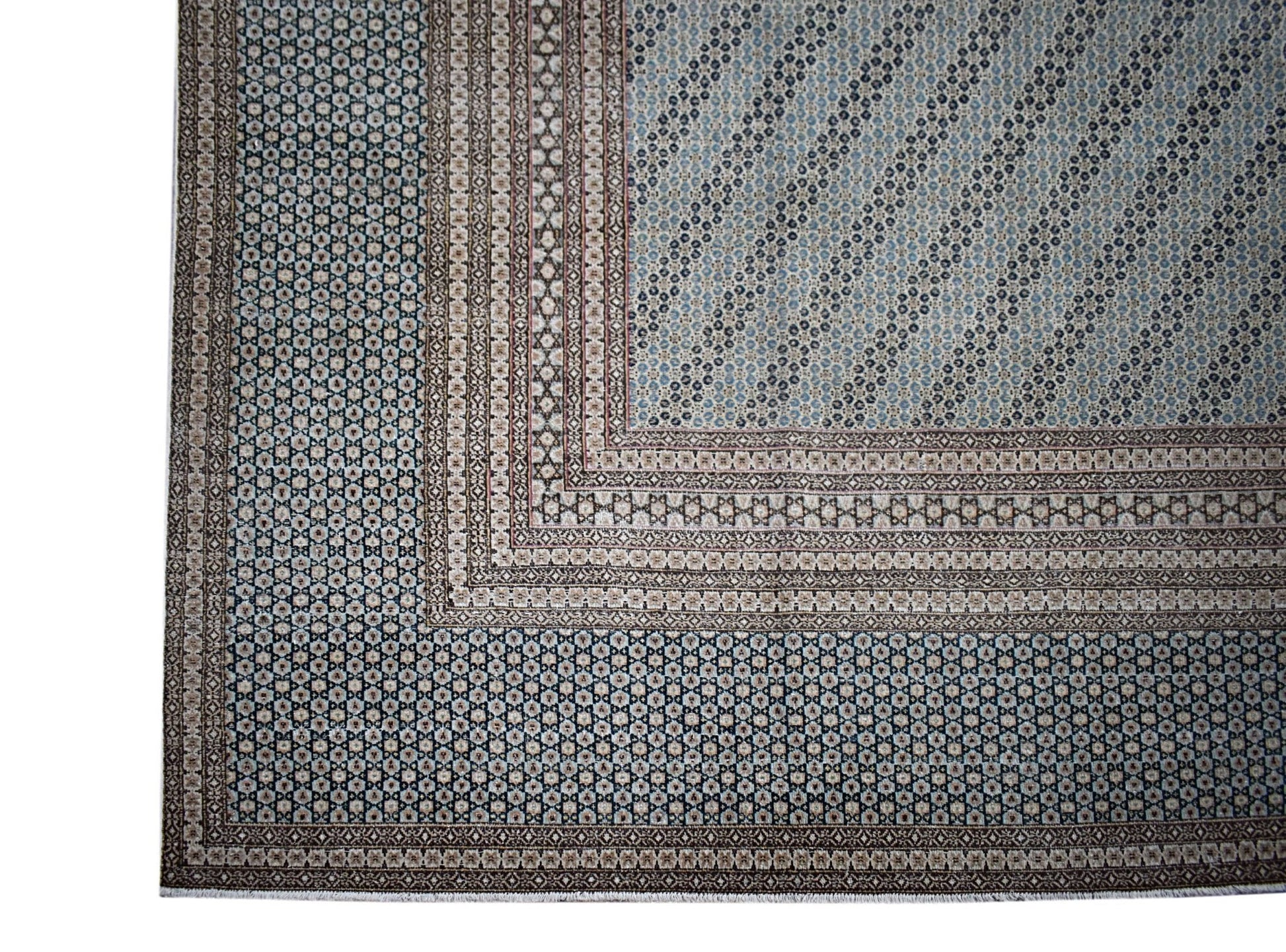 A vintage Persian Kerman rug featuring intricate geometric patterns in blue and beige tones.