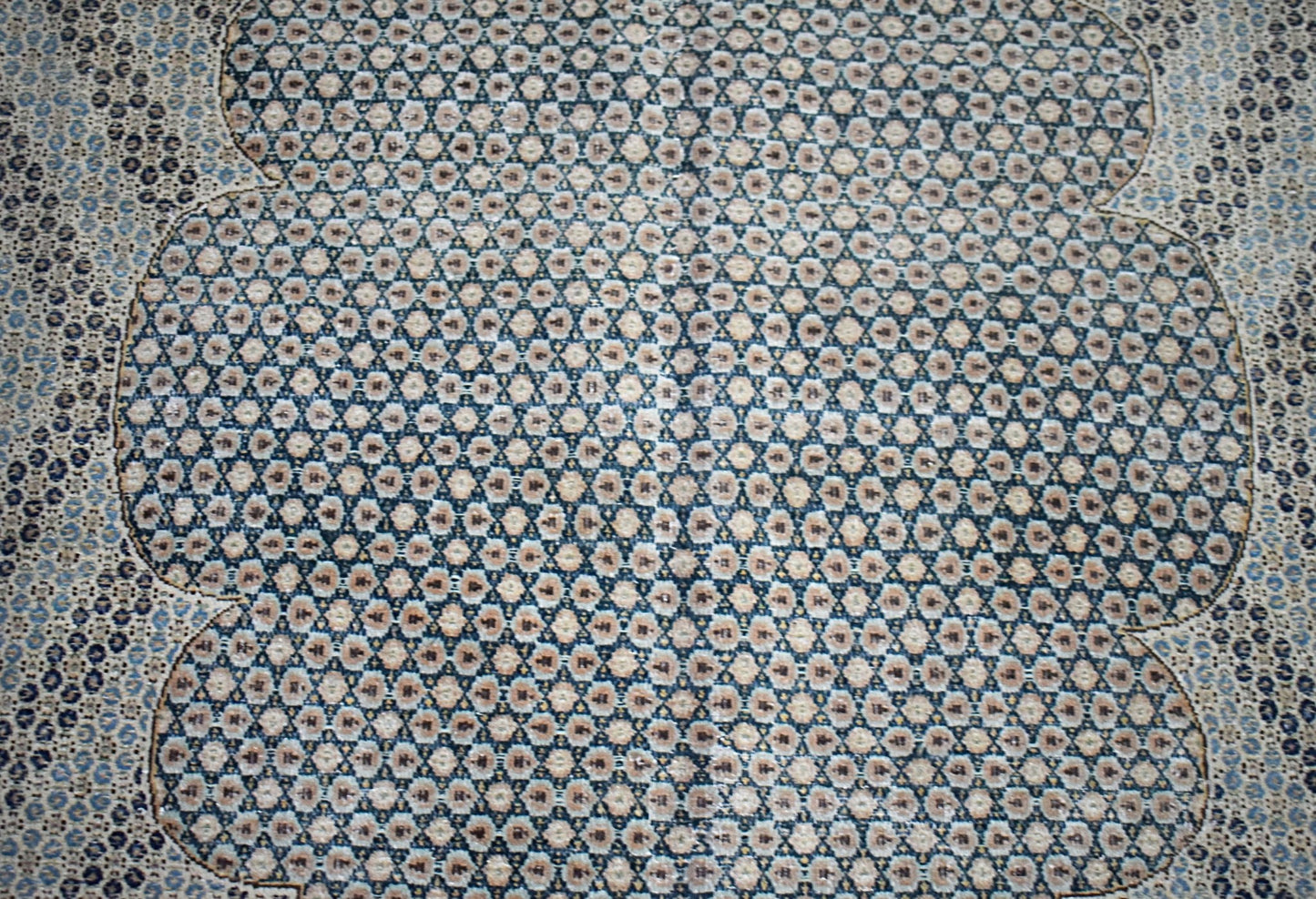 A vintage Persian Kerman rug featuring an intricate, repeating geometric pattern in blue and beige.