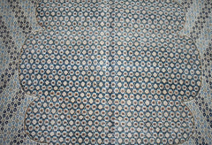 A vintage Persian Kerman rug featuring an intricate, repeating geometric pattern in blue and beige.