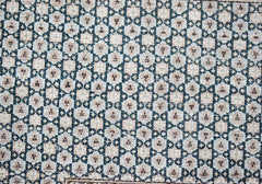 A vintage Persian Kerman rug featuring a repeating geometric pattern in muted tones.