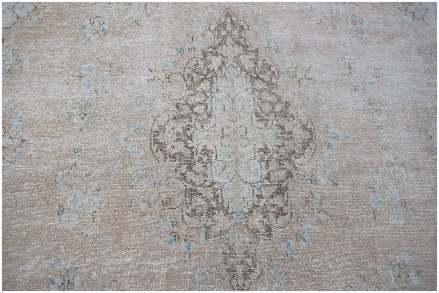 A vintage Persian Kerman rug featuring a central medallion with intricate floral motifs in beige.