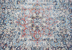 A vintage Persian Kerman rug featuring an intricate floral medallion in blue, red, and cream tones.
