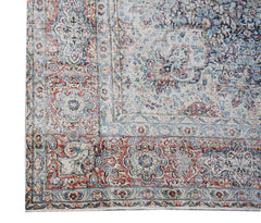 A vintage Persian Kerman rug featuring an intricate floral medallion design in red and blue tones.