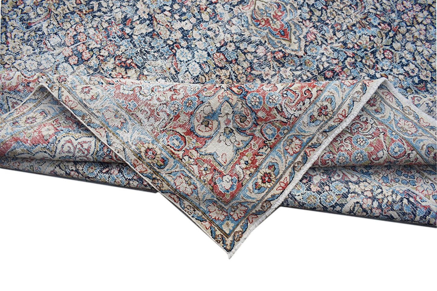 A vintage Persian Kerman rug featuring an intricate floral medallion pattern in blue and red.