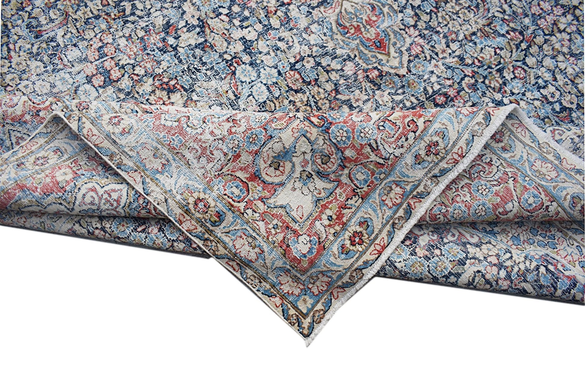 A vintage Persian Kerman rug featuring an intricate floral medallion pattern in blue and red.