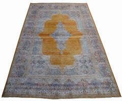 A vintage Persian Kerman rug featuring a central medallion on a golden field with floral borders.