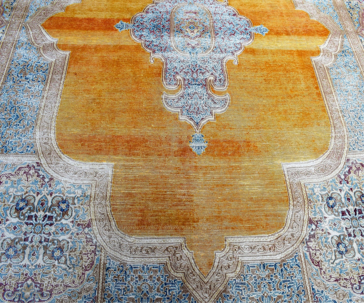 A vintage Persian Kerman rug featuring a central medallion on a vibrant orange field.