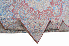 A vintage Persian Kerman rug featuring a floral medallion design in shades of pink and blue.