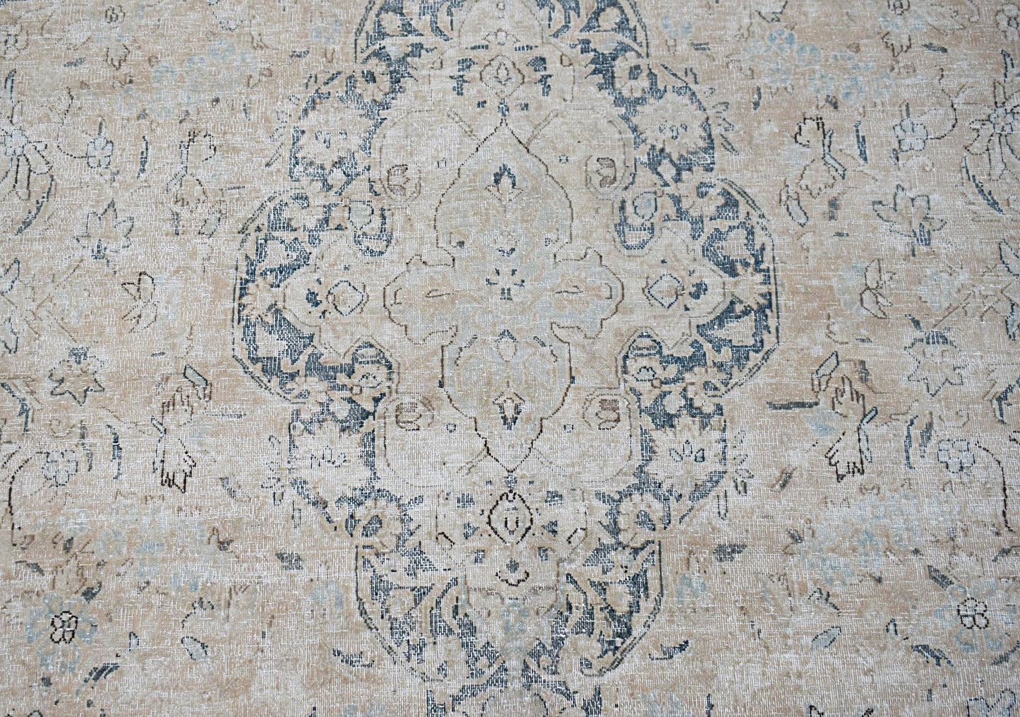 A vintage Persian Kerman rug featuring a central medallion with intricate floral motifs in blue.