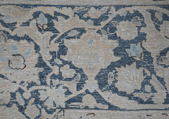 A close-up of a vintage Persian Kerman rug featuring intricate blue and beige floral patterns.