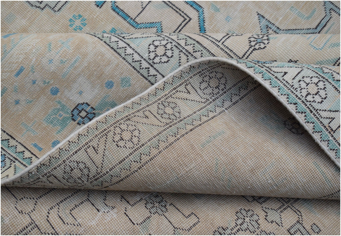 A vintage Persian Kerman rug featuring a beige field with intricate floral patterns and blue accents.
