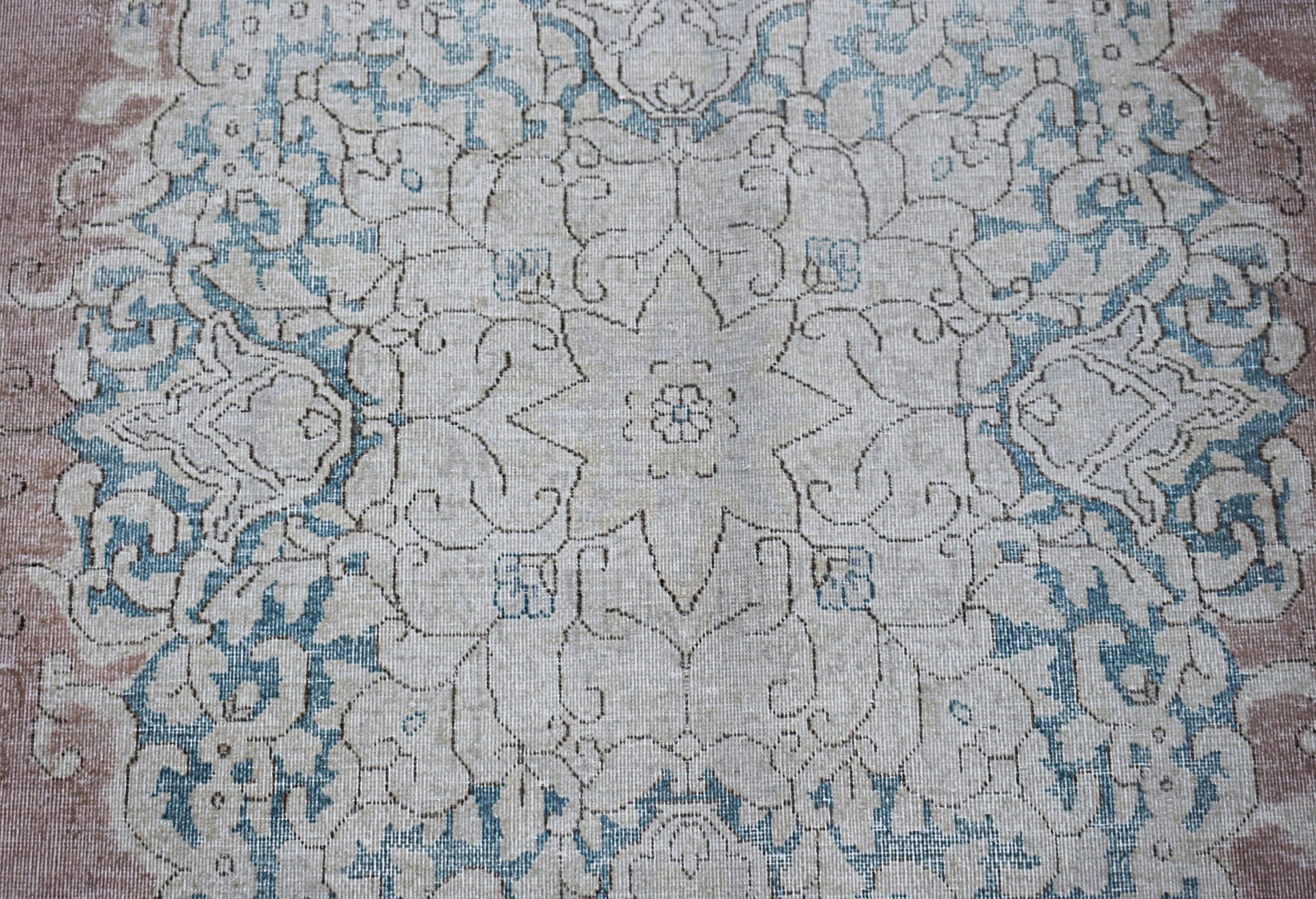 A vintage Persian Kerman rug featuring a central floral medallion in soft blue and beige tones.