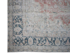 A vintage Persian Kerman rug featuring a faded floral medallion design in soft pink and blue tones.