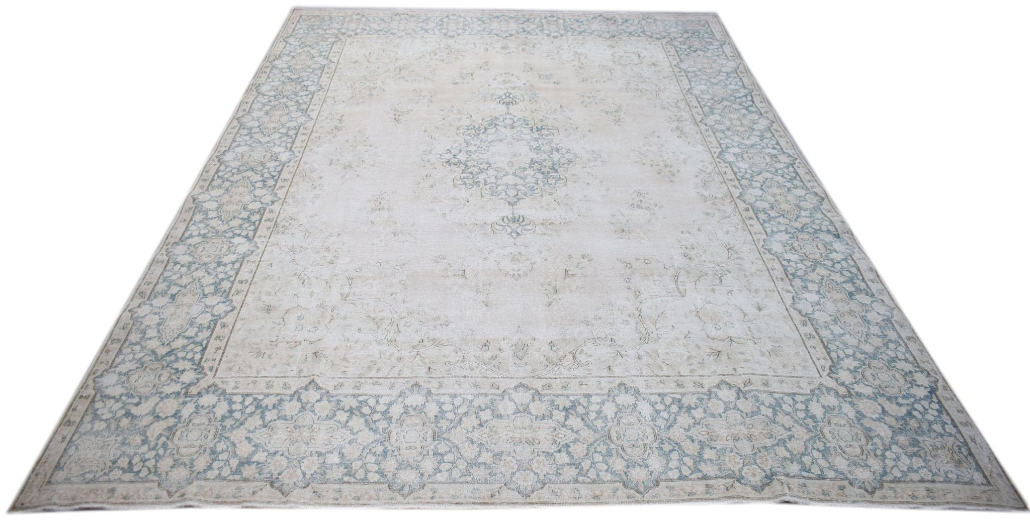 A vintage Persian Kerman rug featuring a central medallion and floral border in soft blue and cream.