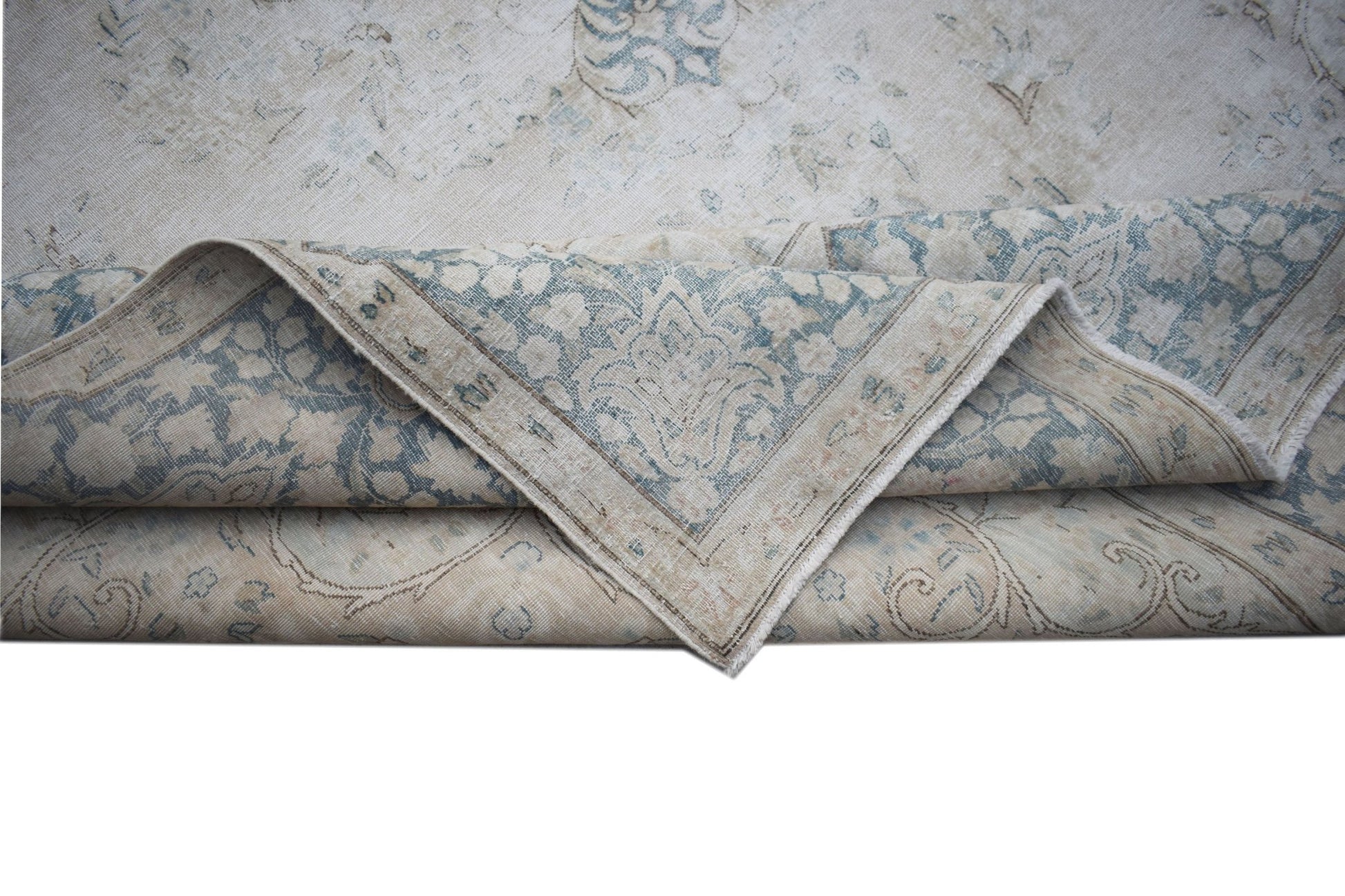 A vintage Persian Kerman rug featuring a faded blue and beige floral medallion pattern.