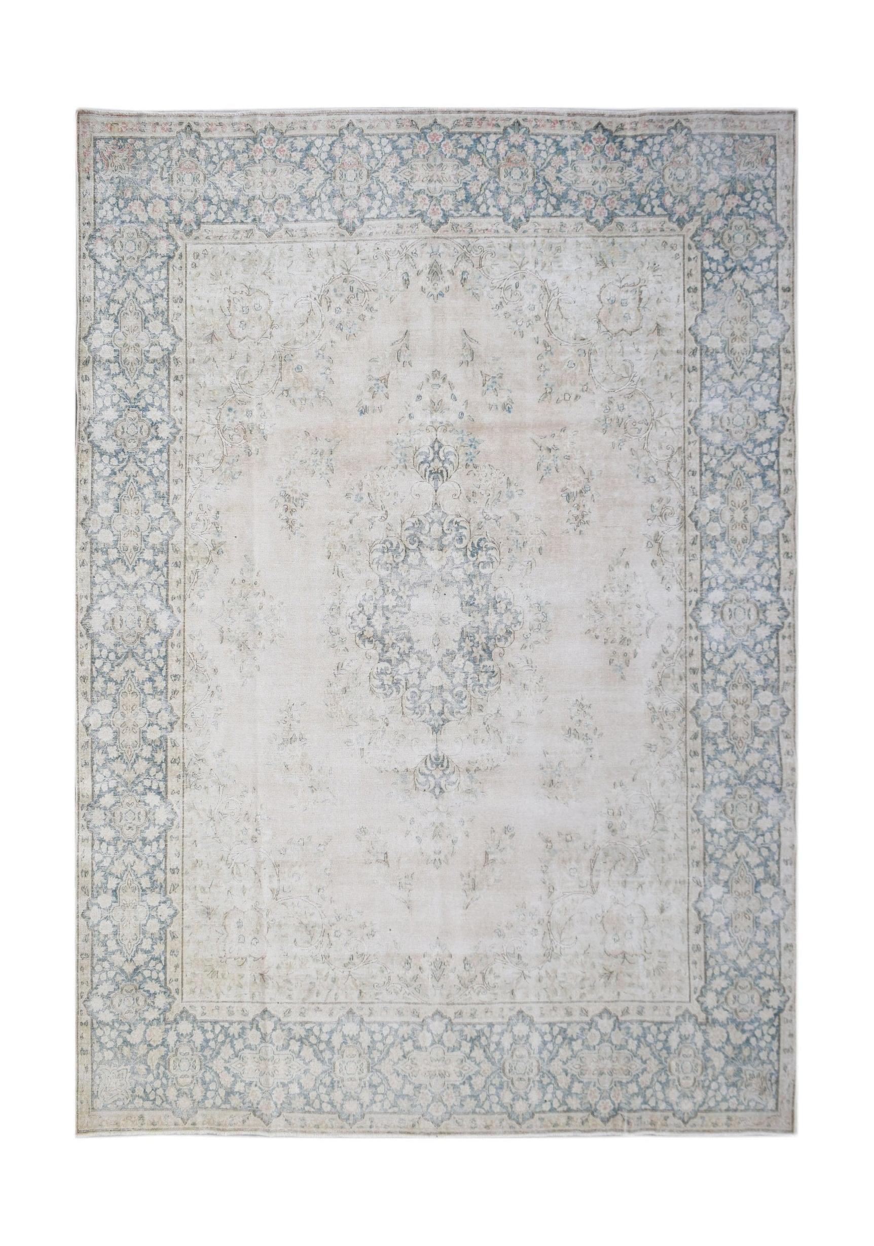A vintage Persian Kerman rug featuring a central floral medallion in soft blue and cream tones.