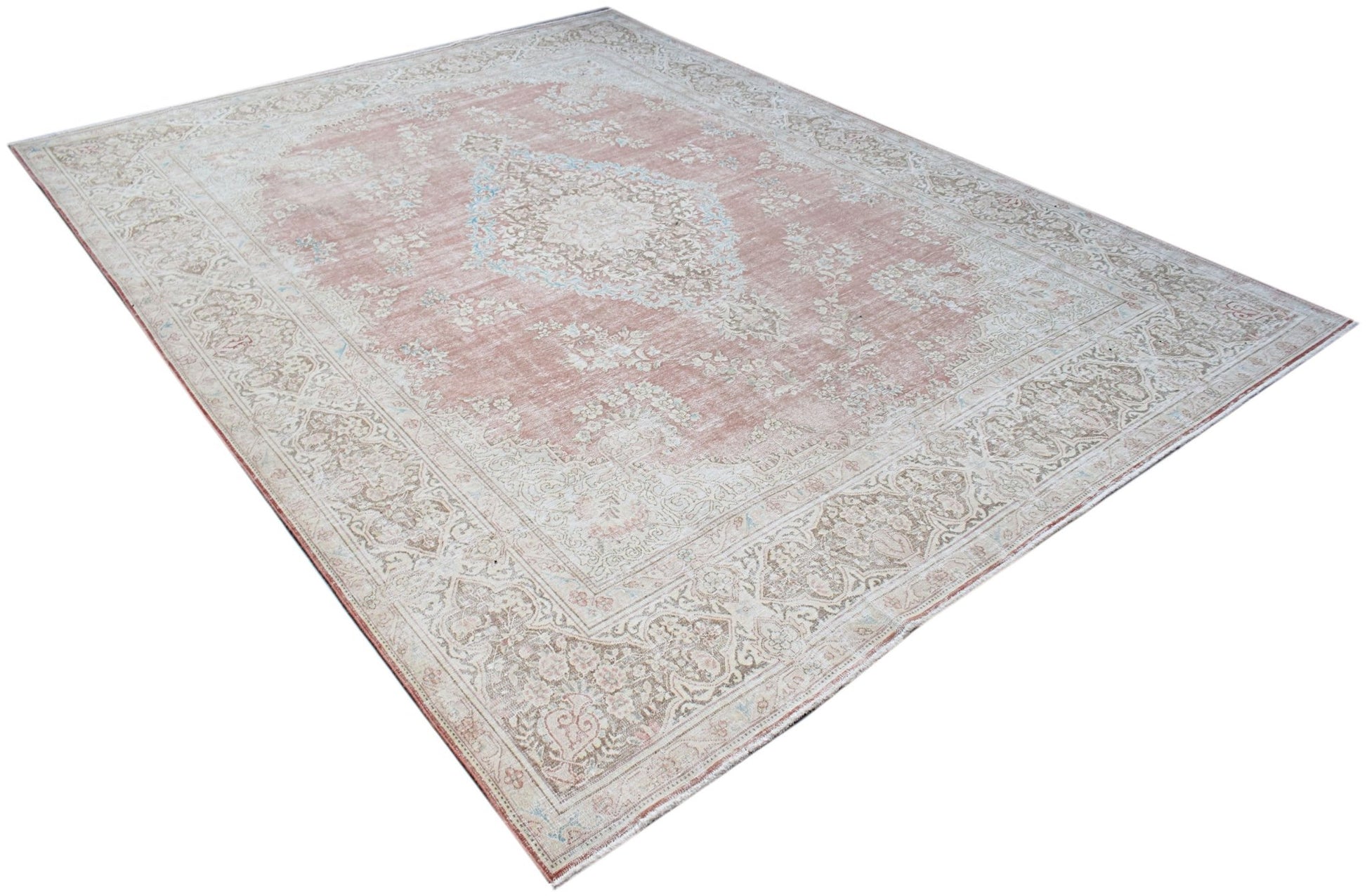 A vintage Persian Kerman rug featuring a central medallion and intricate floral patterns in pink.