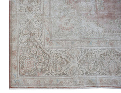 A vintage Persian Kerman rug featuring an intricate floral medallion design in soft muted tones.