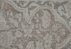 A close-up view of a vintage Persian Kerman rug featuring intricate floral patterns in muted tones.