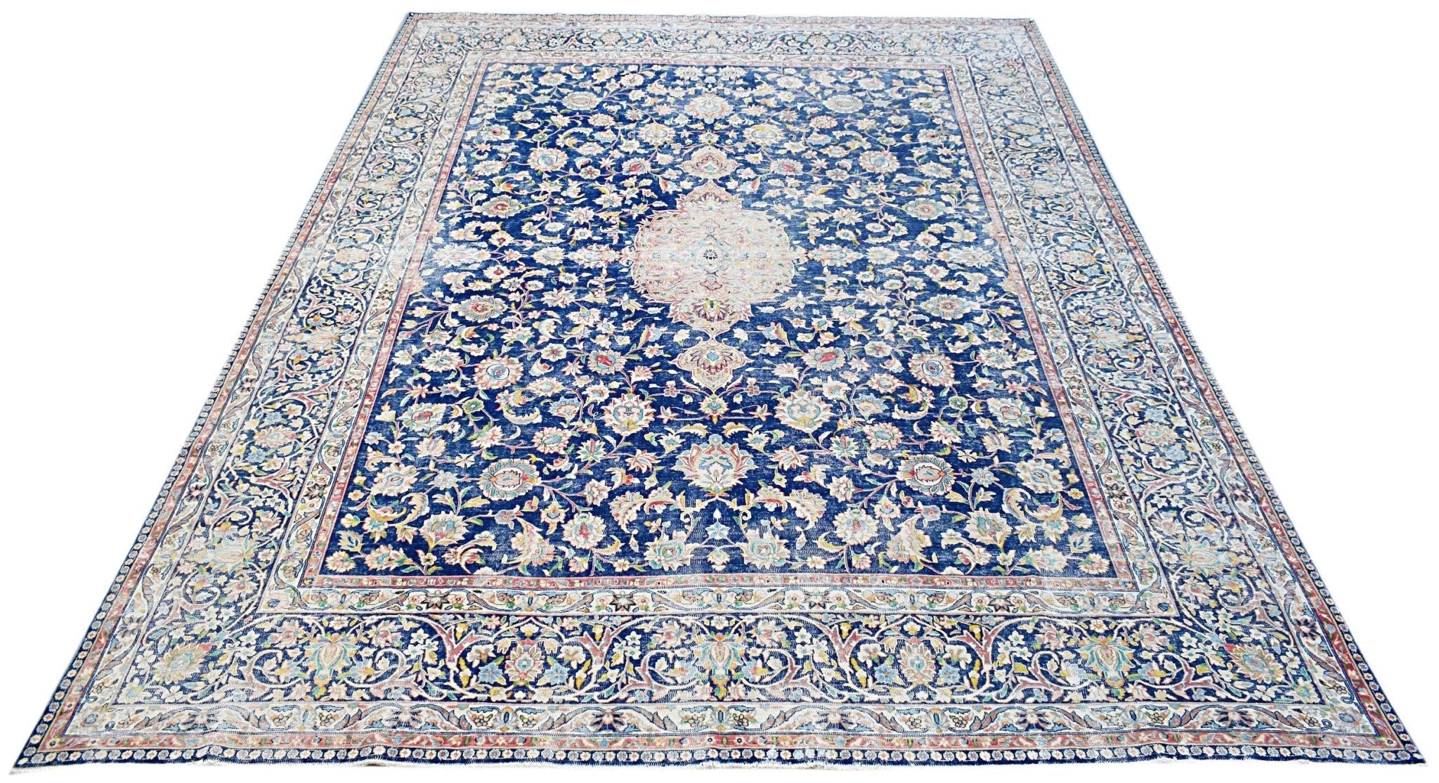 A vintage Persian Kerman rug featuring a central medallion and intricate floral patterns in blue.