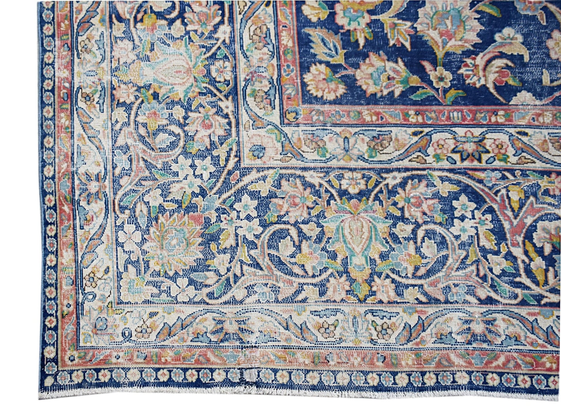 A vintage Persian Kerman rug featuring intricate floral patterns in blue, cream, and soft pink.