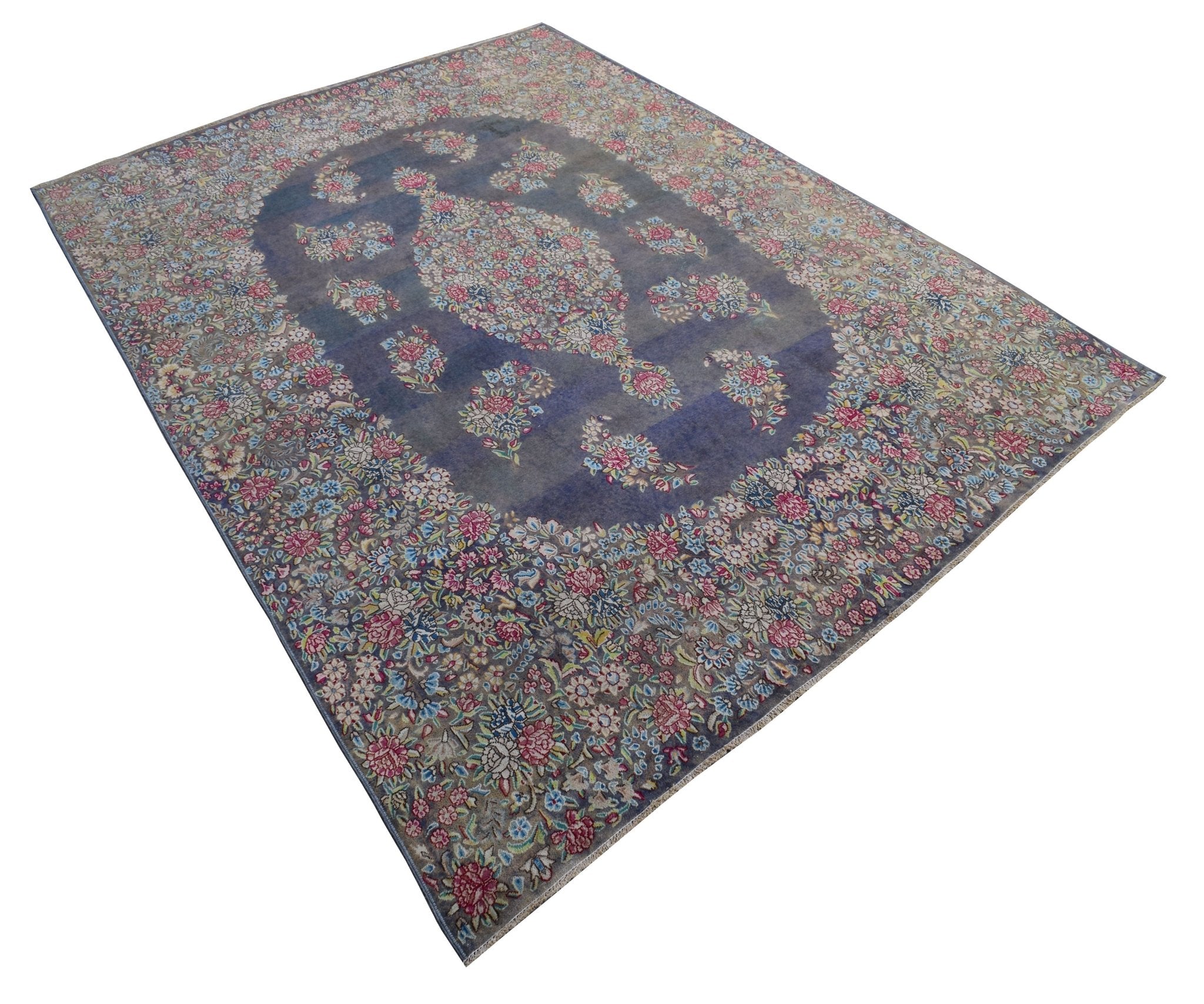 A vintage Persian Kerman rug featuring a central floral medallion on a blue field.