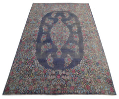 A vintage Persian Kerman rug featuring a central floral medallion on a blue field.