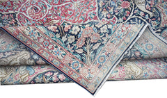 A vintage Persian Kerman rug featuring an intricate floral pattern in pink, blue, and cream tones.