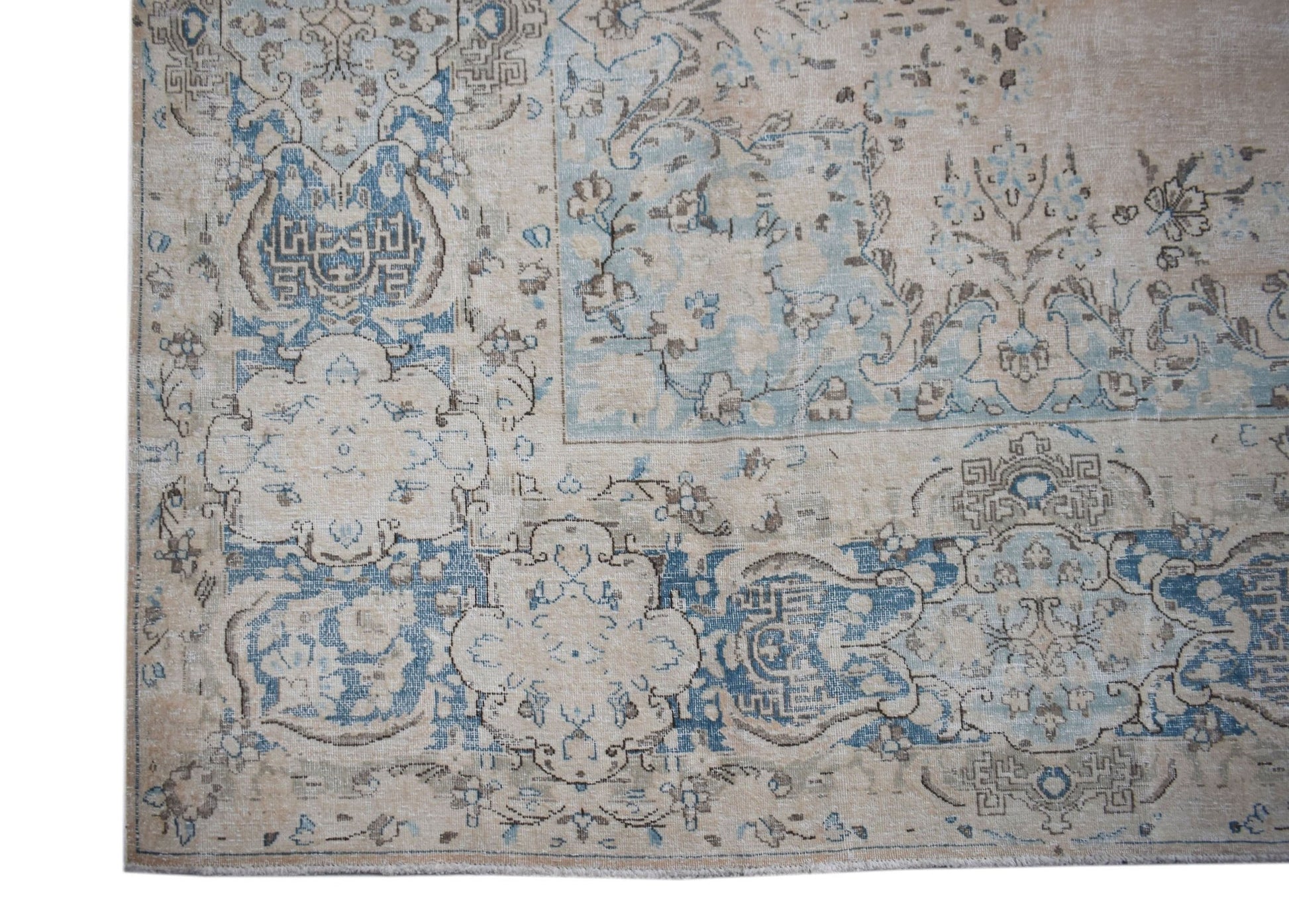 A vintage Persian Kerman rug featuring intricate blue and beige floral and medallion patterns.