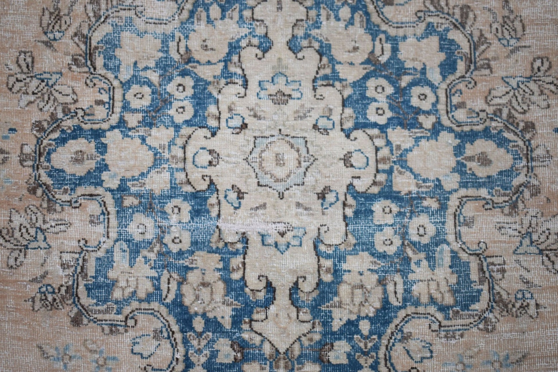 A vintage Persian Kerman rug featuring a central medallion with intricate blue and beige florals.