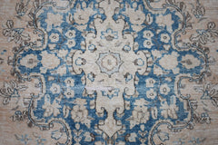 A vintage Persian Kerman rug featuring a central medallion with intricate blue and beige florals.
