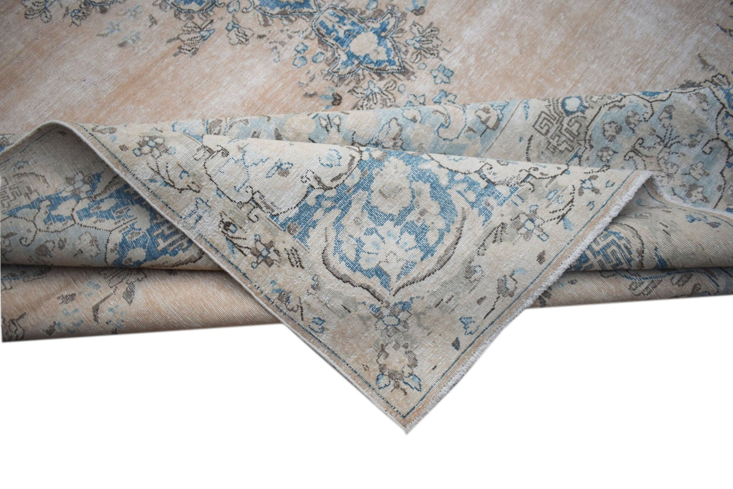 A vintage Persian Kerman rug featuring a faded floral medallion pattern in blue and beige tones.