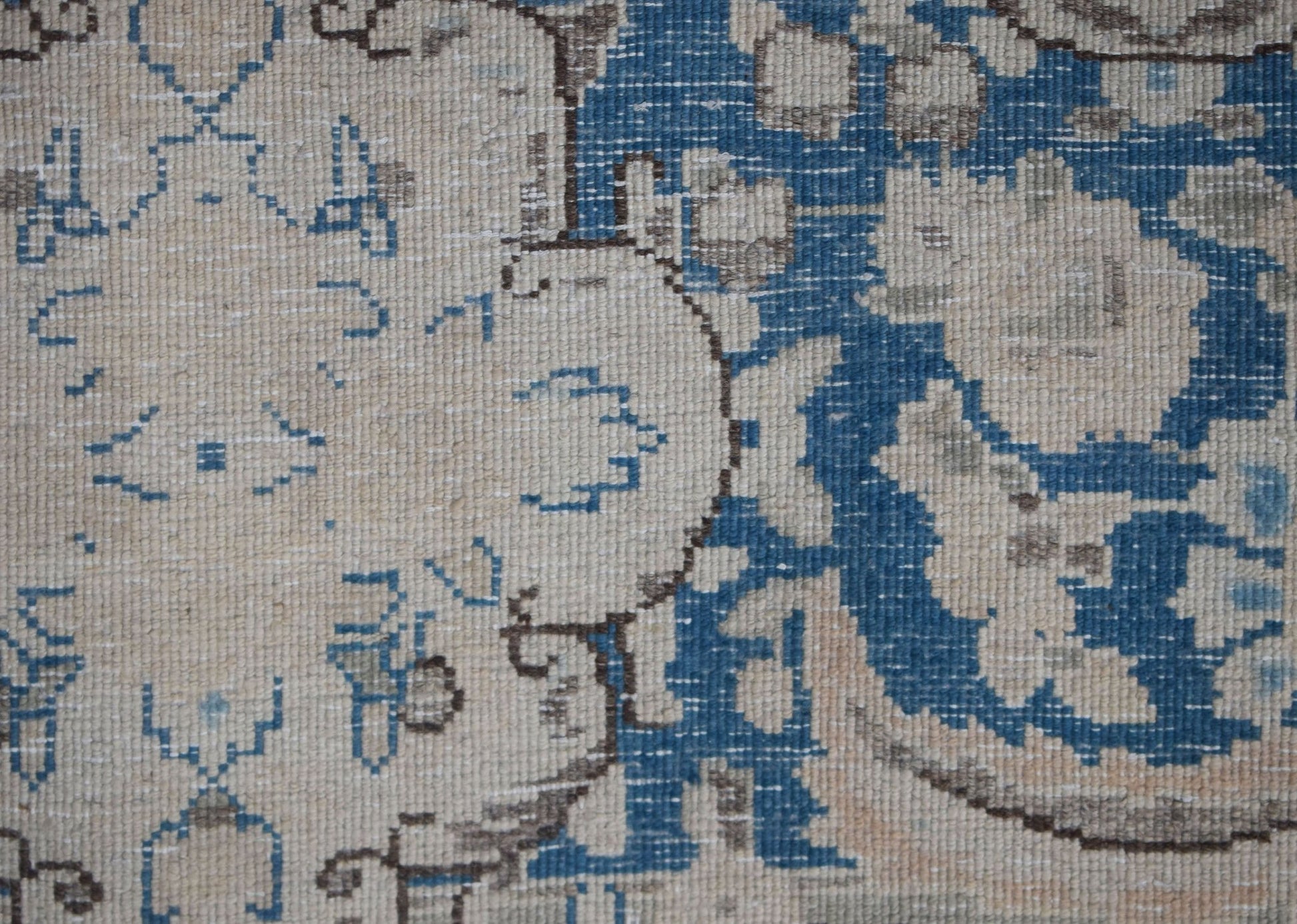 A close-up of a vintage Persian Kerman rug featuring intricate blue and cream floral patterns.