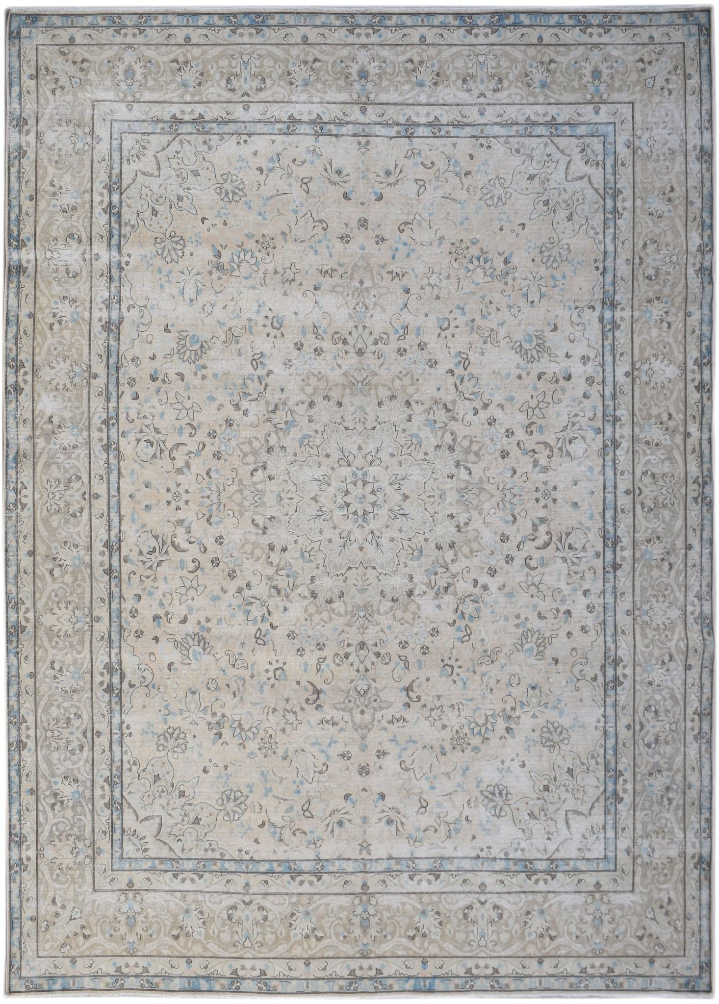 A vintage Persian Kerman rug featuring a central floral medallion in soft beige and blue tones.