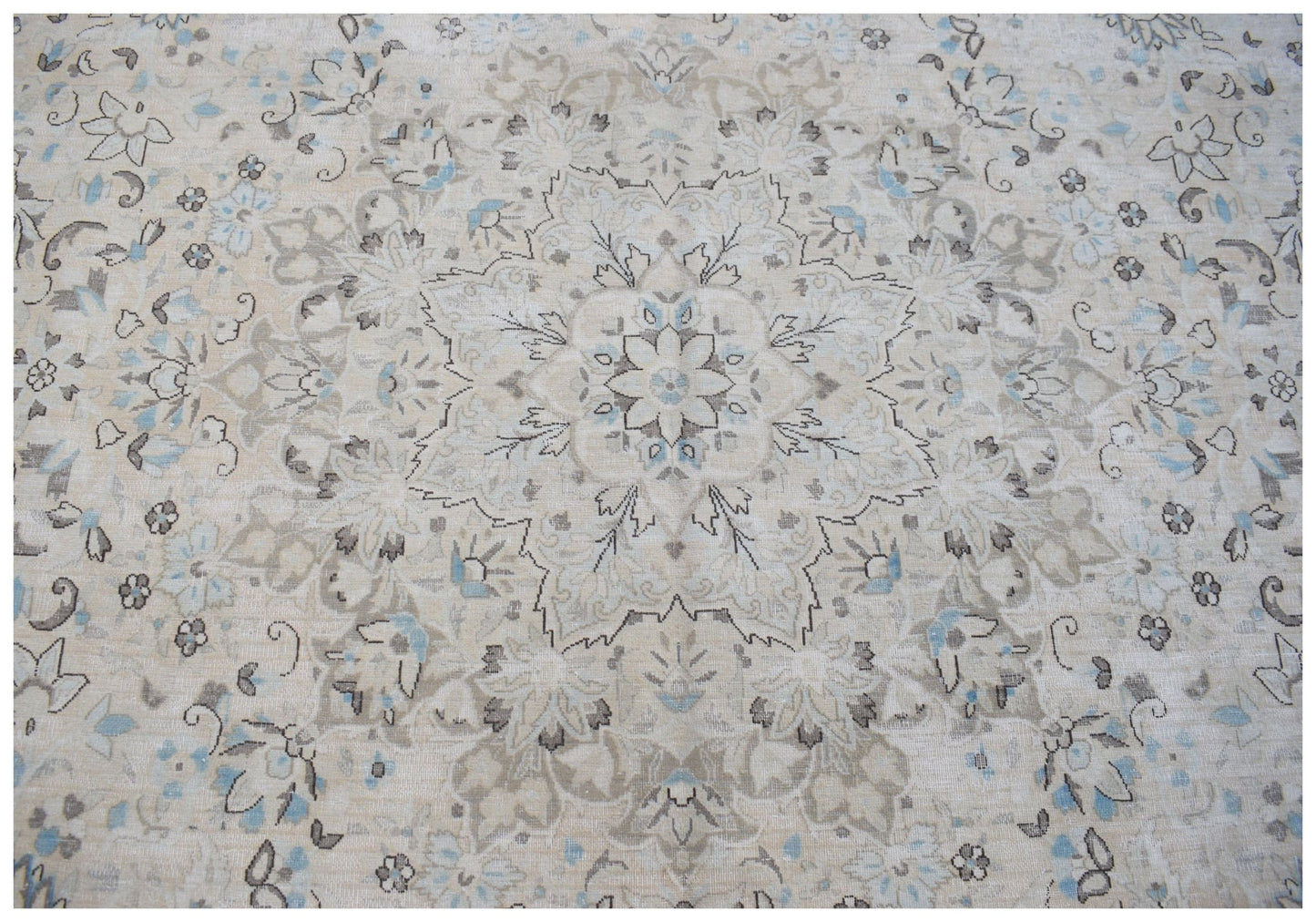 A vintage Persian Kerman rug featuring a central floral medallion in soft beige and blue tones.