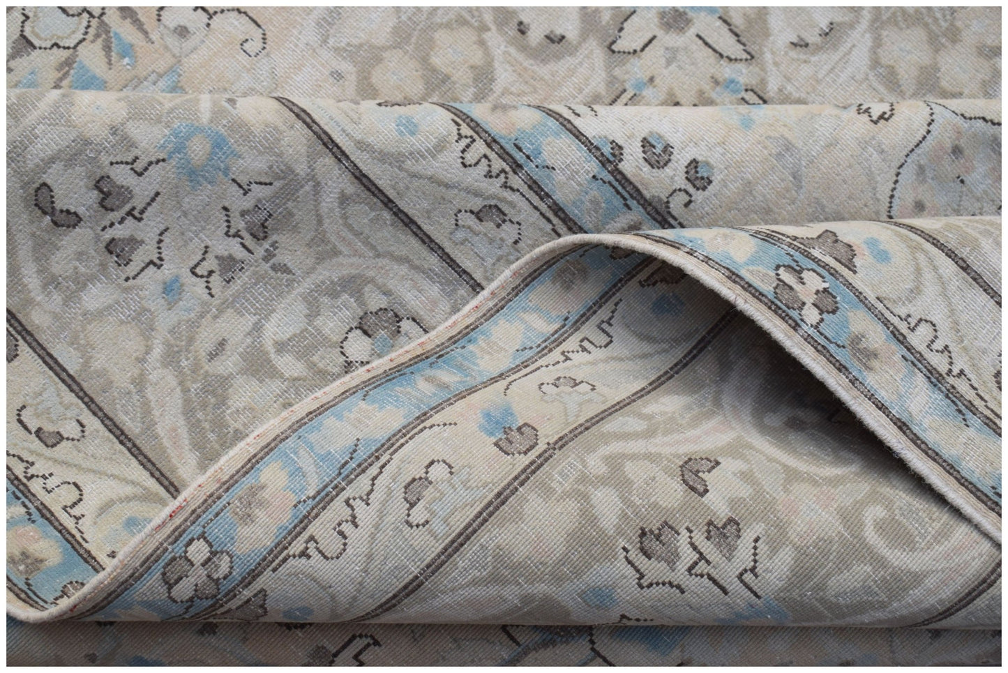 A vintage Persian Kerman rug featuring a soft floral pattern in blue and beige tones.
